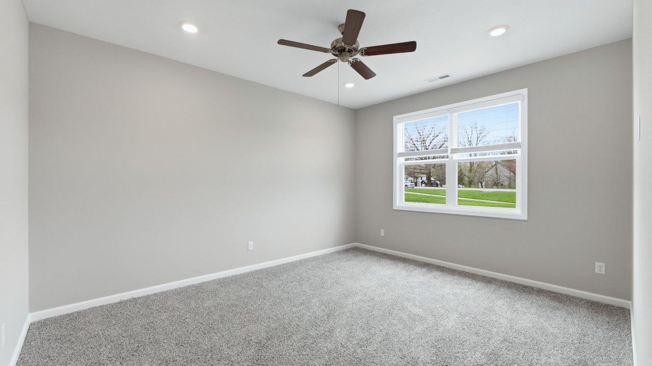 primary bedroom with ensuite bathroom and walk-in closet with carpet flooring, ceiling fan, and 2 windows
