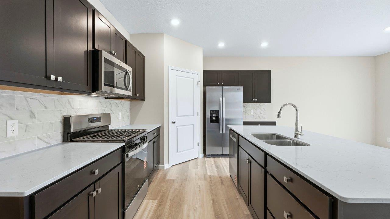 kitchen with sarsaparilla cabinets, tile backsplash, corner pantry, stainless steel appliances, and center island