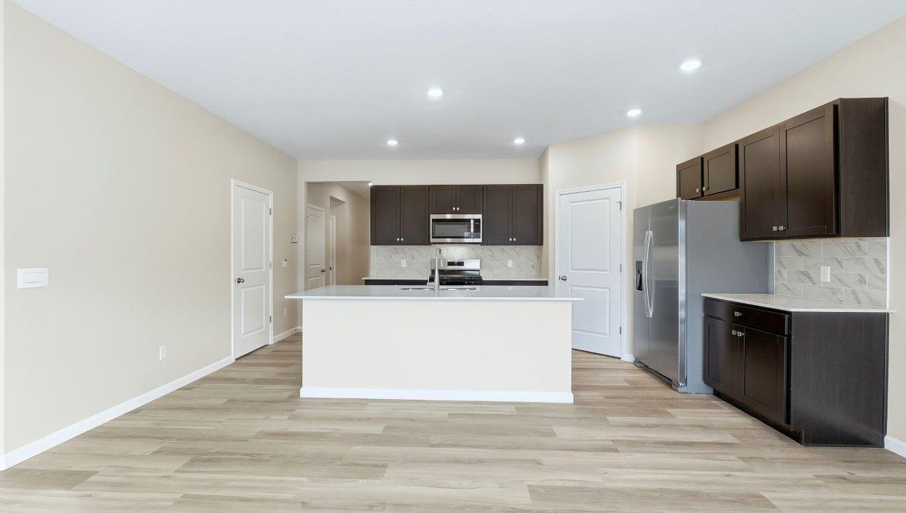 kitchen with sarsaparilla cabinets, tile backsplash, corner pantry, stainless steel appliances, and center island