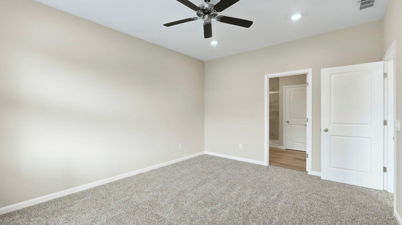 primary bedroom with carpet and fan with ensuite bath and closet