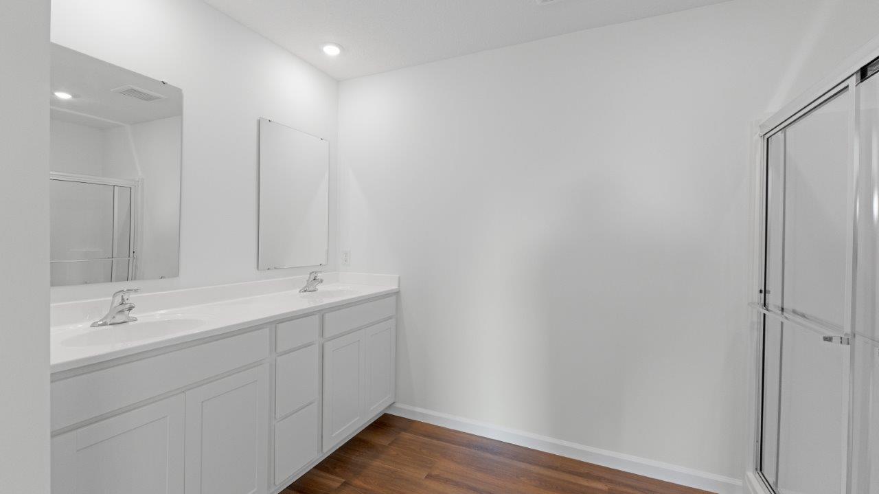 elm primary ensuite bathroom with dual sinks, lvp, walk-in shower, linen closet, and private toilet