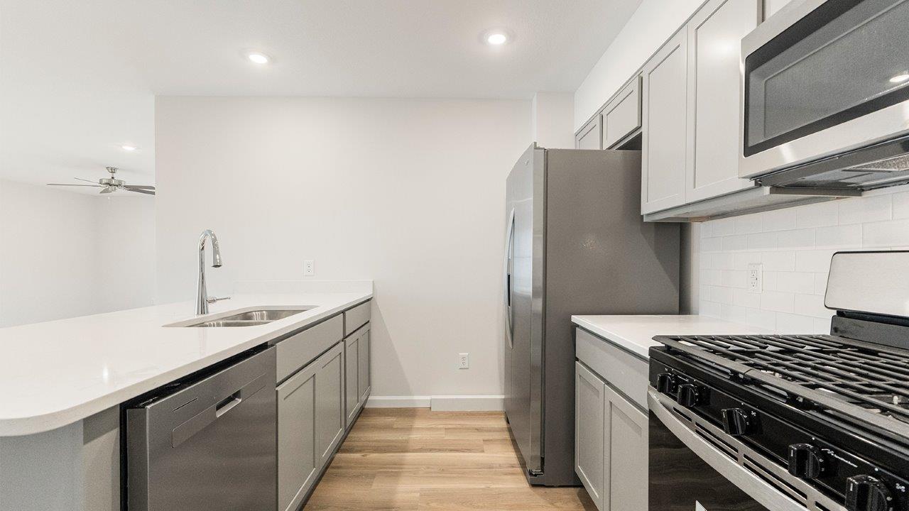kitchen with grey cabinets, whirlpool stainless steel appliances, white quartz countertops, lvp flooring, and bar seating at island