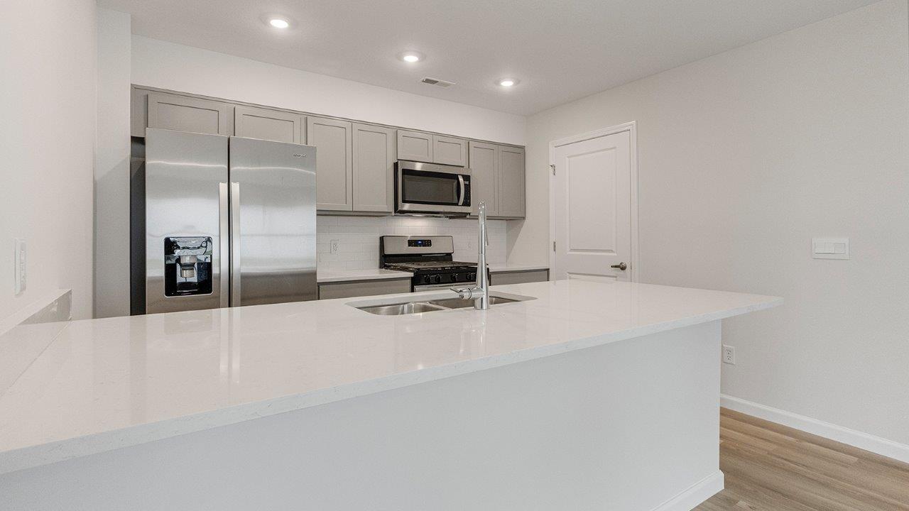 kitchen with grey cabinets, whirlpool stainless steel appliances, white quartz countertops, lvp flooring, and bar seating at island