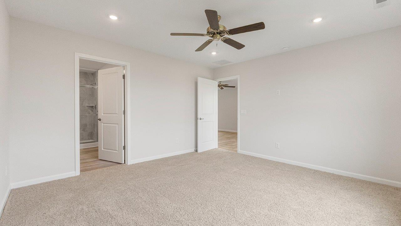 primary bedroom with carpet flooring, 2 windows, fan, and ensuite bath/closet