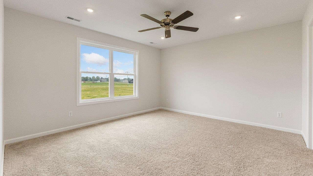 primary bedroom with carpet flooring, 2 windows, fan, and ensuite bath/closet