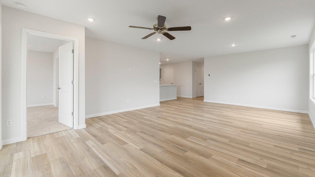 living room open floorplan with mohawk avery lvp flooring, ceiling fan, and windows