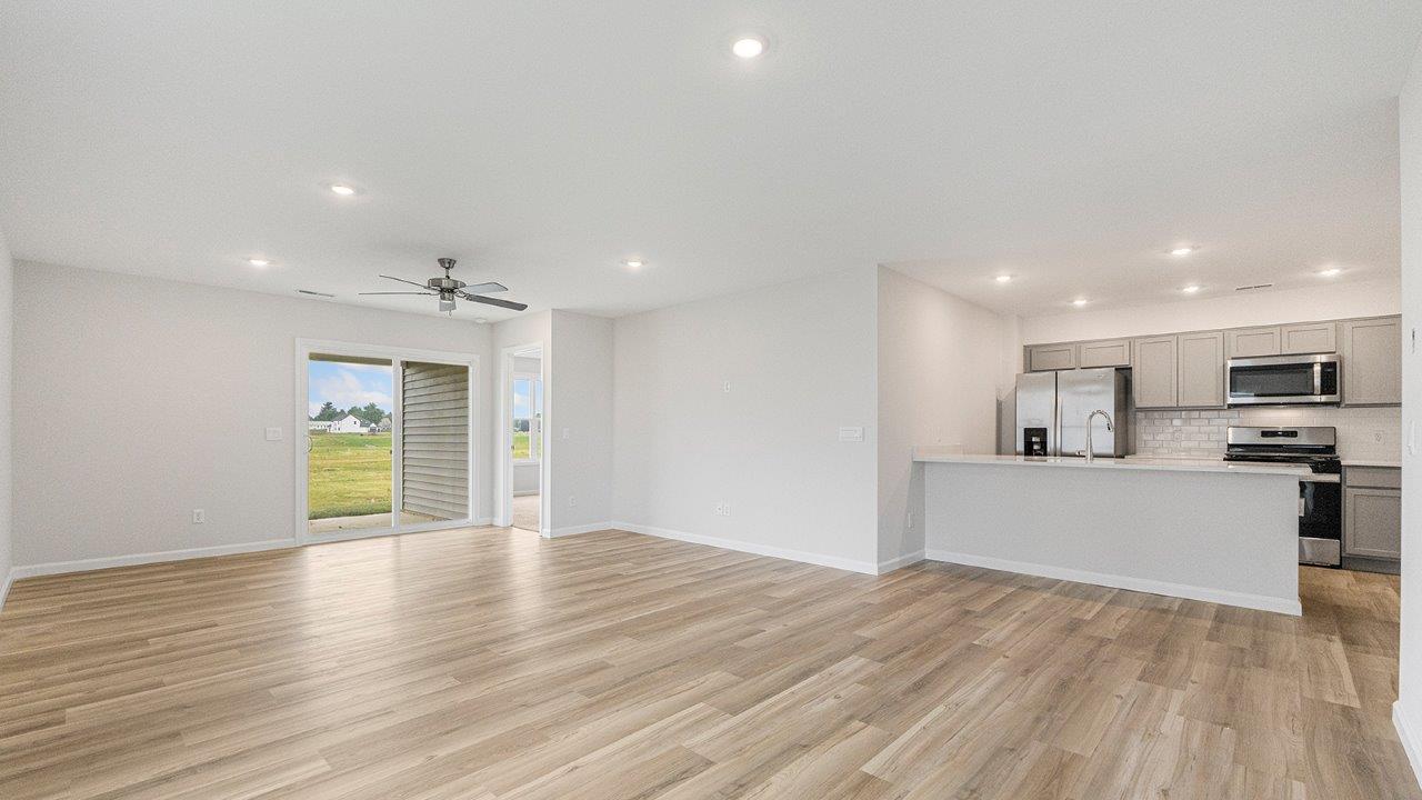living room open floorplan with mohawk avery lvp flooring, ceiling fan, and windows