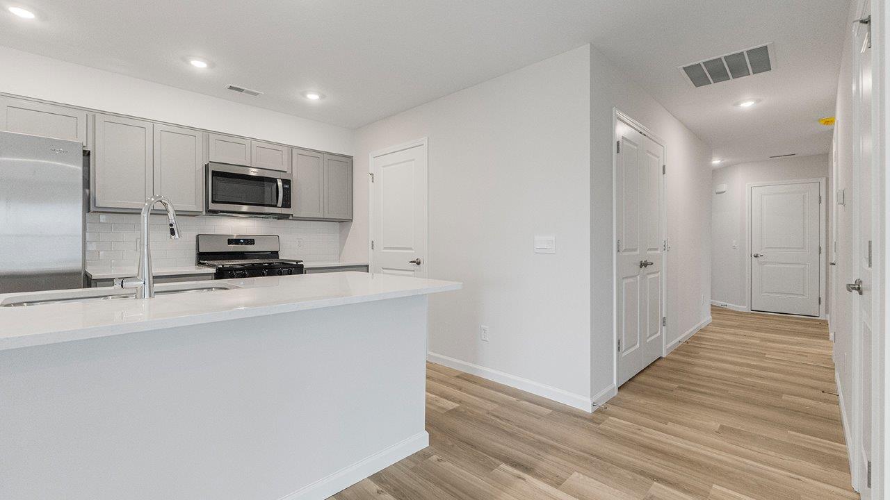 kitchen with grey cabinets, whirlpool stainless steel appliances, white quartz countertops, lvp flooring, and bar seating at island