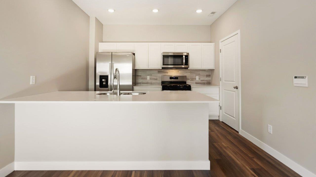 livingston lakes paired villas olsen kitchen with white cabinetry, quartz countertops, tile backsplash, and stainless steel appliances