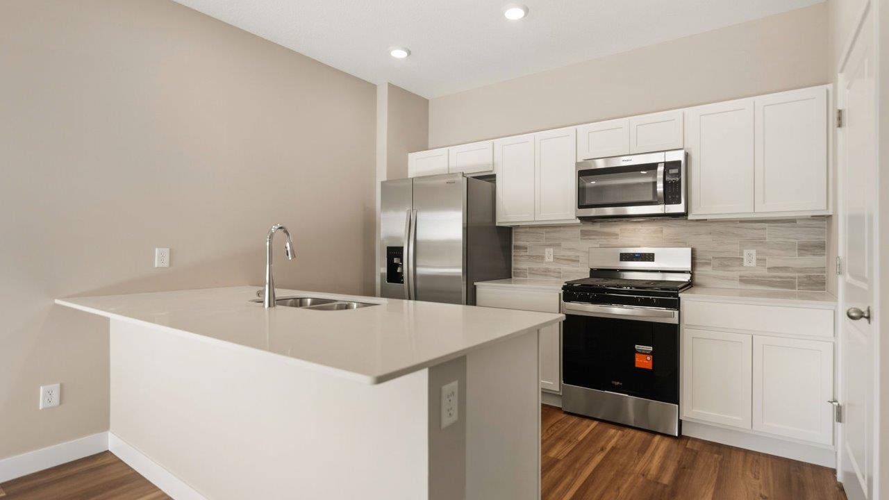 livingston lakes paired villas olsen kitchen with white cabinetry, quartz countertops, tile backsplash, and stainless steel appliances