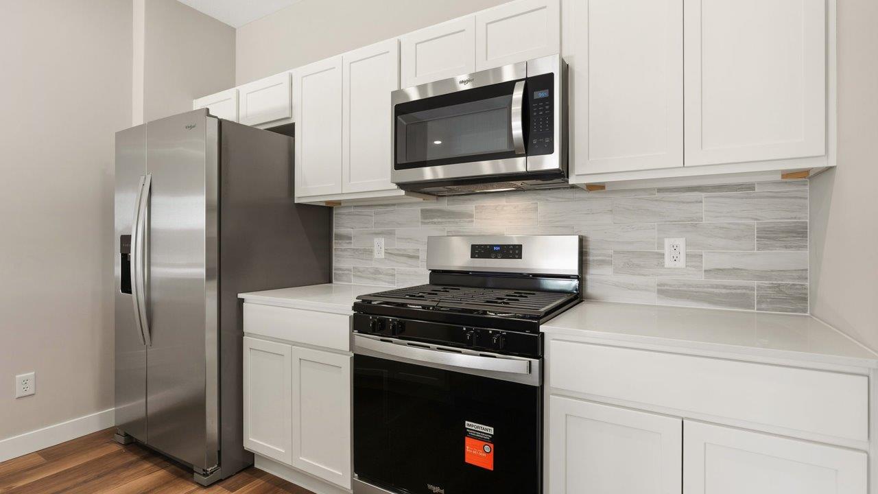 livingston lakes paired villas olsen kitchen with white cabinetry, quartz countertops, tile backsplash, and stainless steel appliances