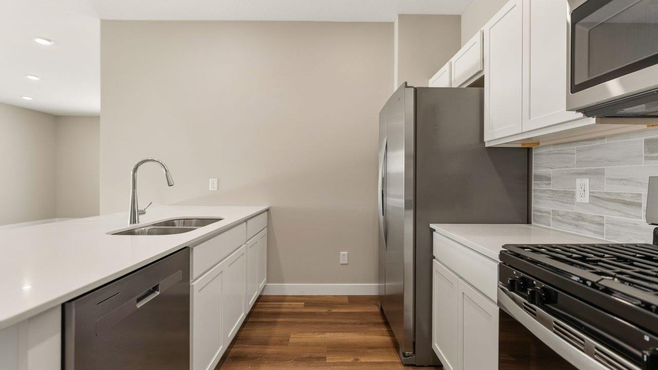 livingston lakes paired villas olsen kitchen with white cabinetry, quartz countertops, tile backsplash, and stainless steel appliances