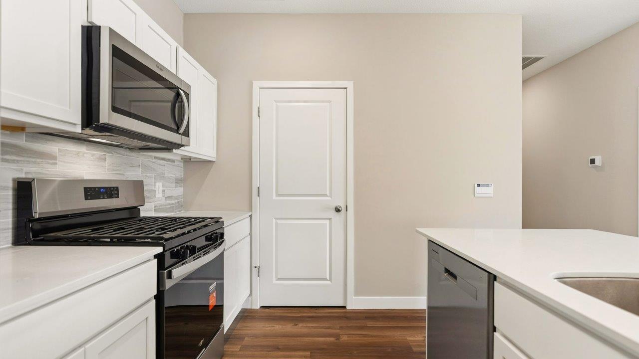 livingston lakes paired villas olsen kitchen with white cabinetry, quartz countertops, tile backsplash, and stainless steel appliances