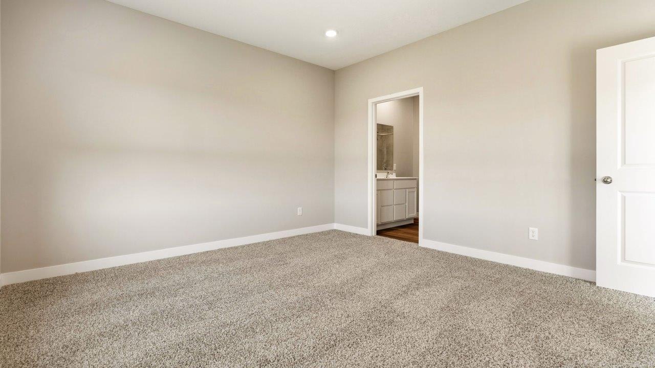 livingston lakes paired villas olsen primary bedroom with beige carpet flooring, 2 large windows, and ensuite bathroom and walk in closet