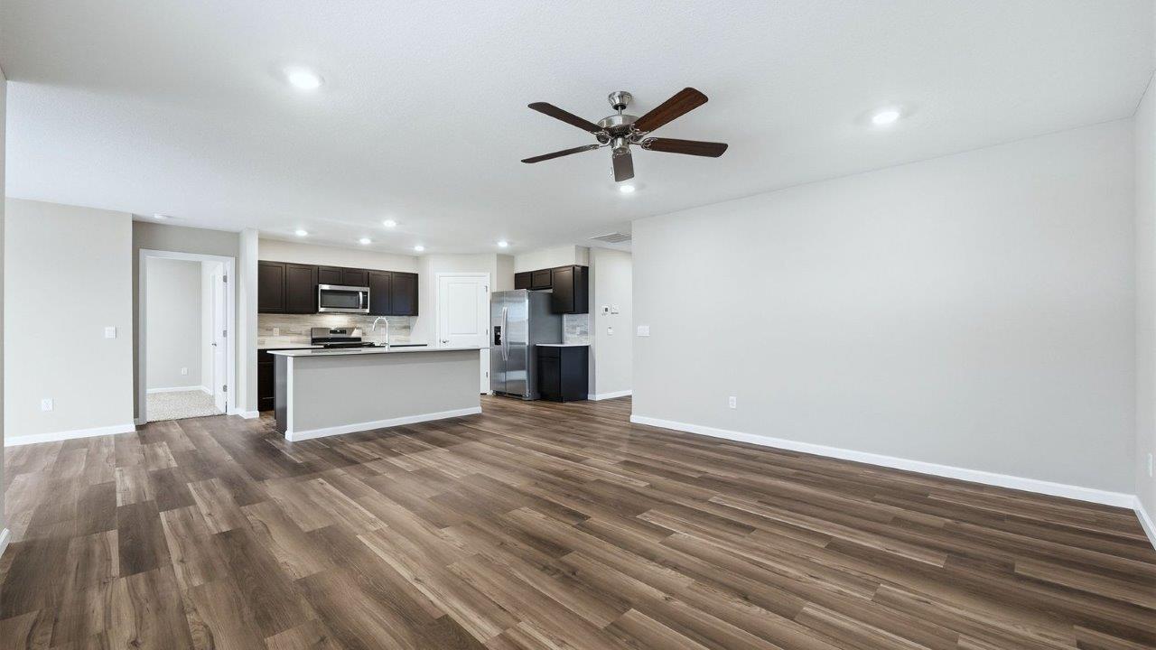 kitchen with mohawk lvp, stainless steel appliances, sarsaparilla shaker cabinets, quartz countertops, corner pantry, and center island with bar seating