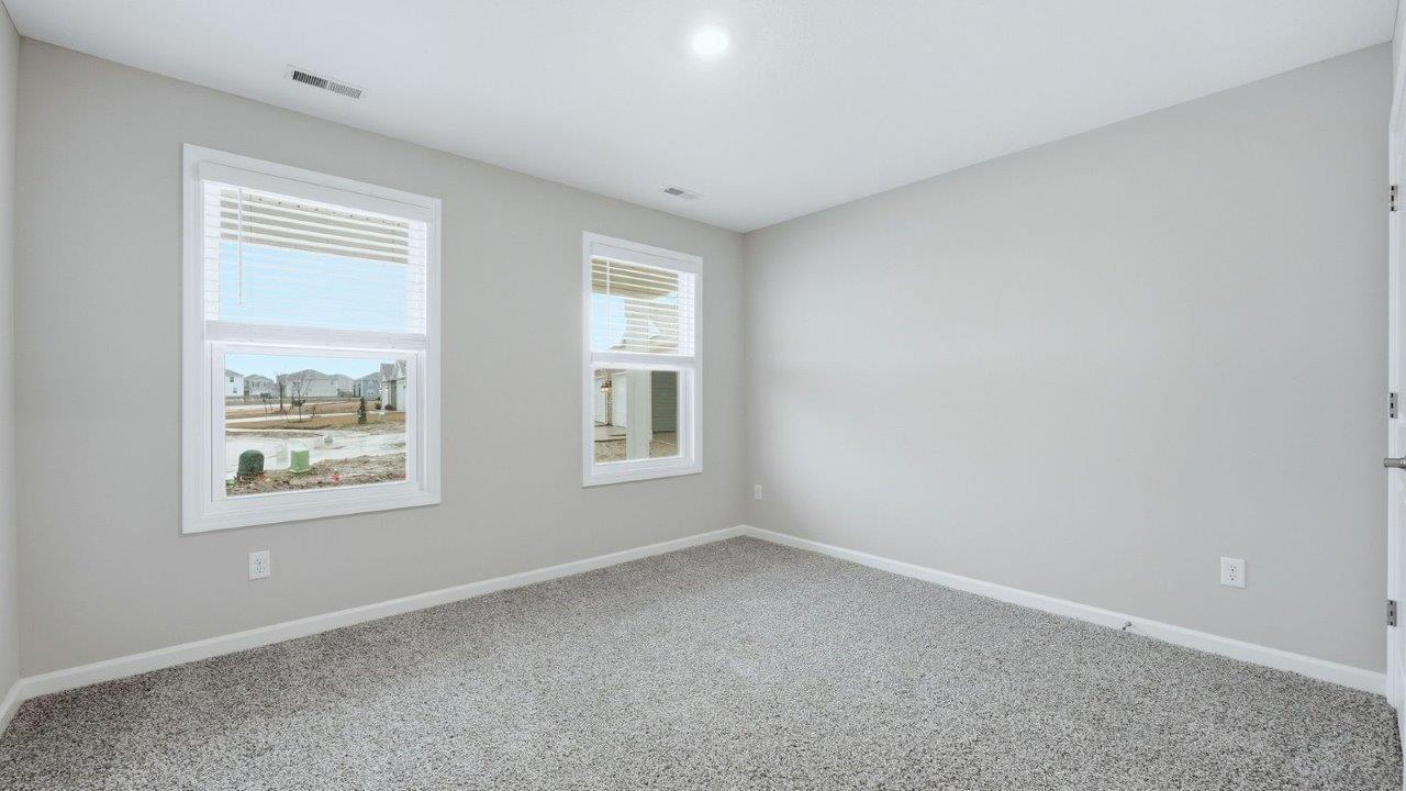 bedroom 2 with beige carpet, popular grey walls, closet, and 2 windows