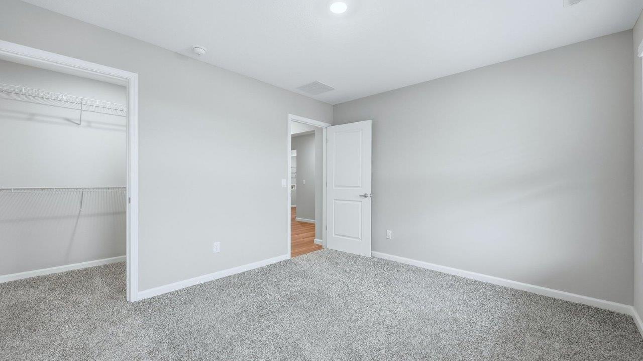 bedroom 2 with beige carpet, popular grey walls, closet, and 2 windows