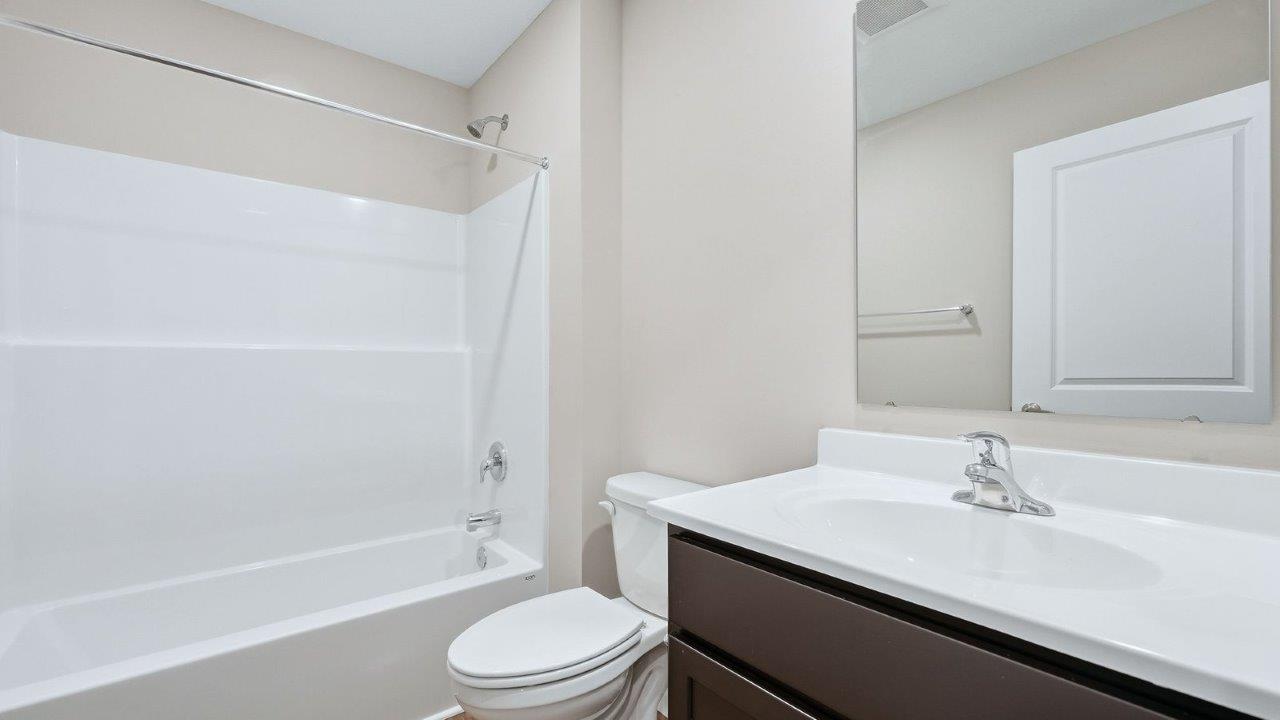 full bathroom single vanity sink with sarsaparilla cabinets and tub shower
