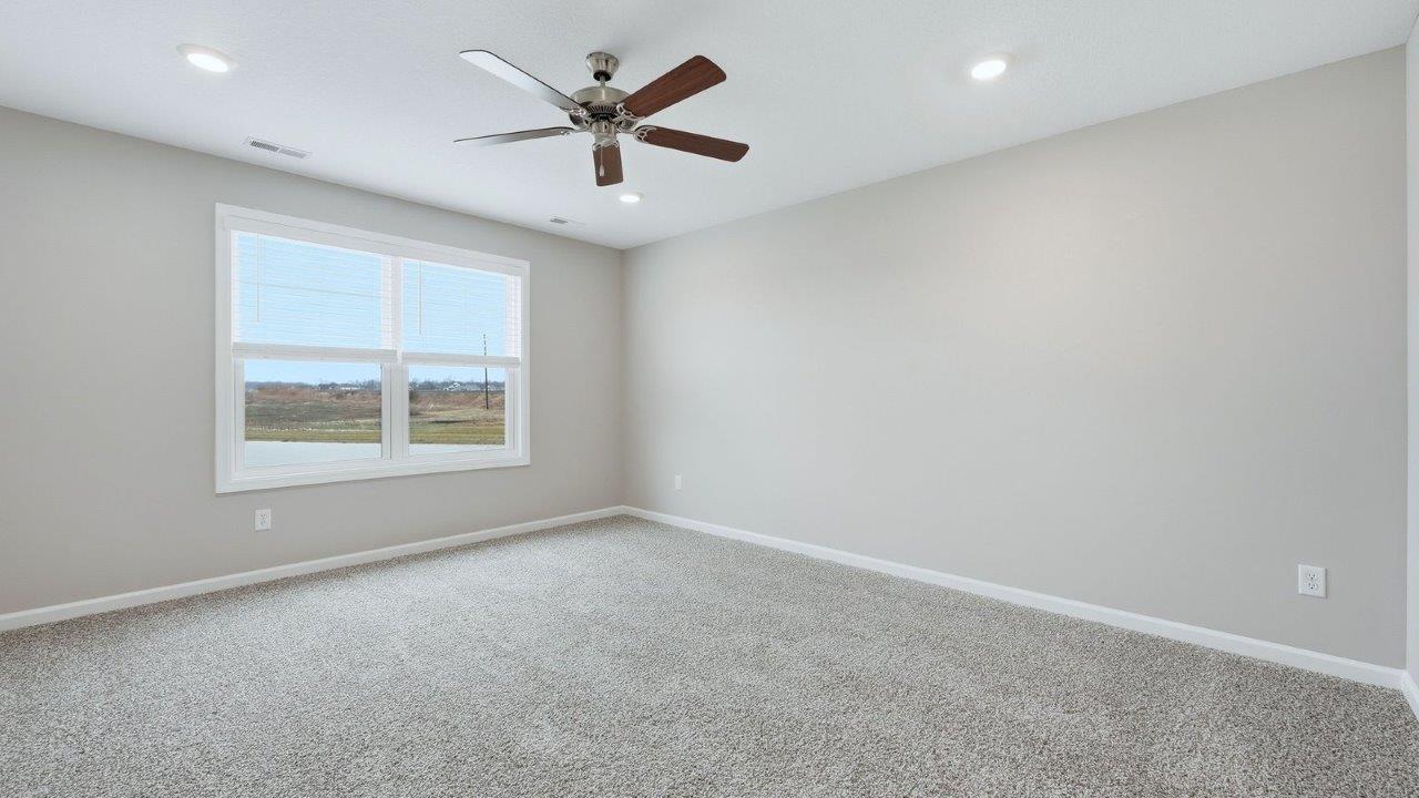 primary bedroom with beige carpet, popular grey walls, ceiling fan, and ensuite bathroom and walk-in closet