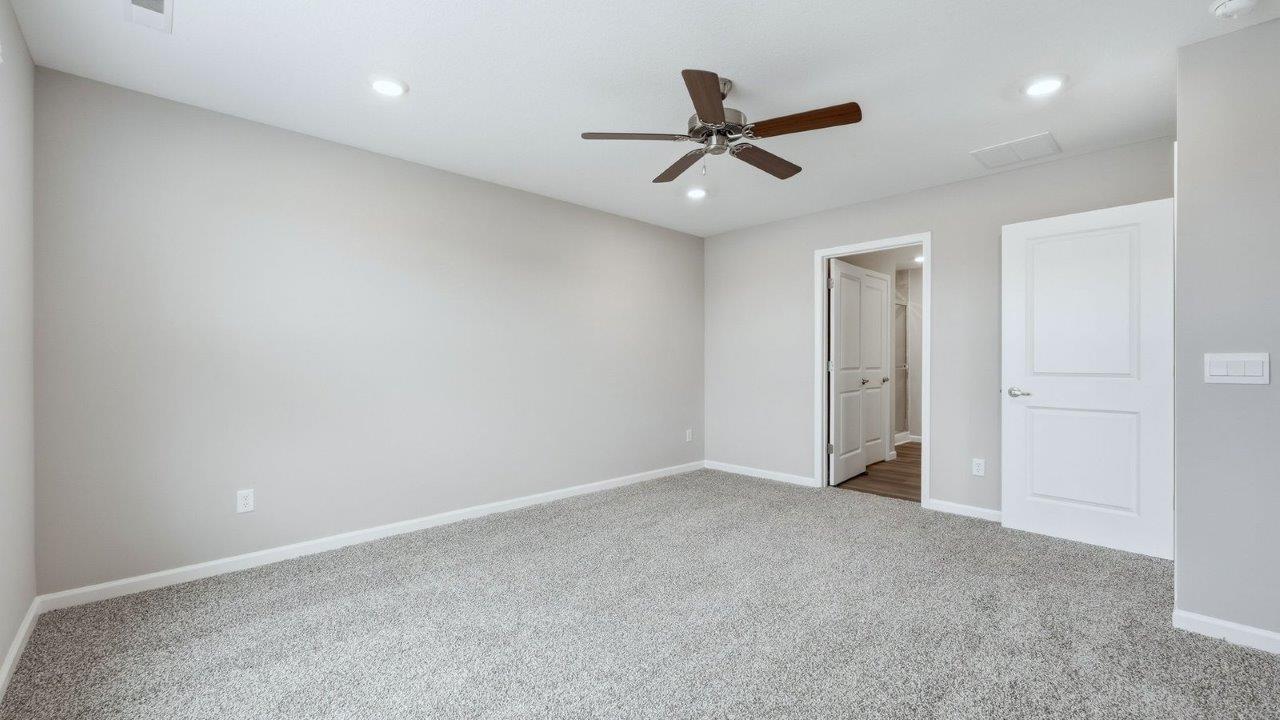 primary bedroom with beige carpet, popular grey walls, ceiling fan, and ensuite bathroom and walk-in closet