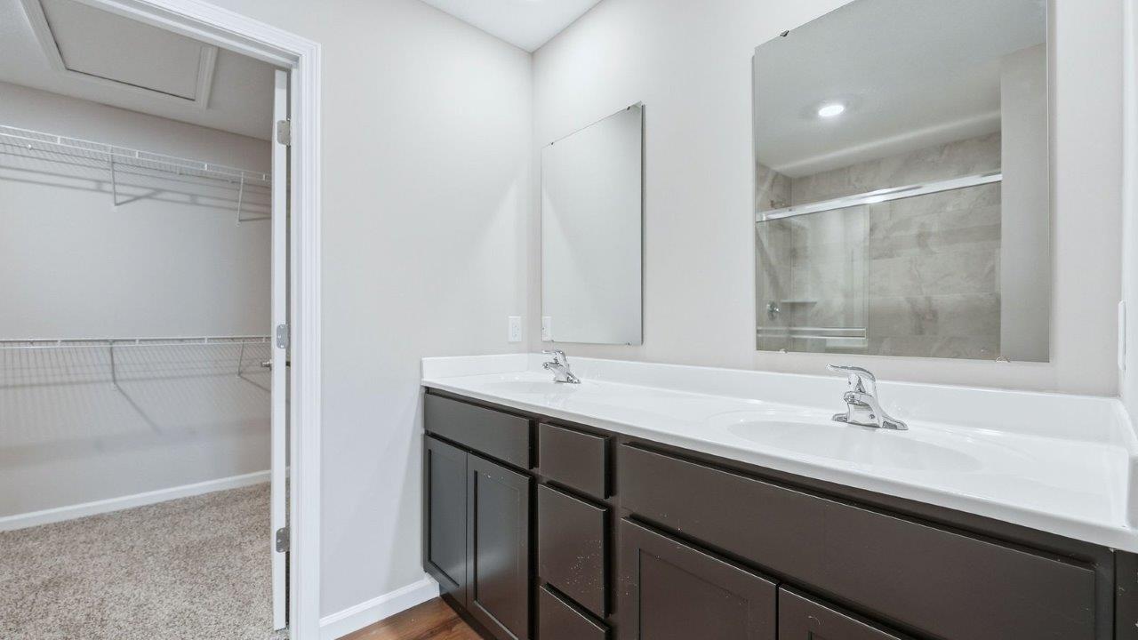 primary ensuite bathroom with dual vanity sinks, quartz counters, sarsaparilla cabinets, lvp flooring, private water room, and walk-in ceramic tile shower
