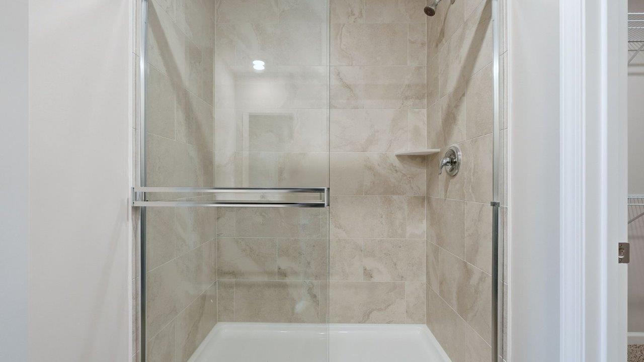 primary ensuite bathroom with dual vanity sinks, quartz counters, sarsaparilla cabinets, lvp flooring, private water room, and walk-in ceramic tile shower