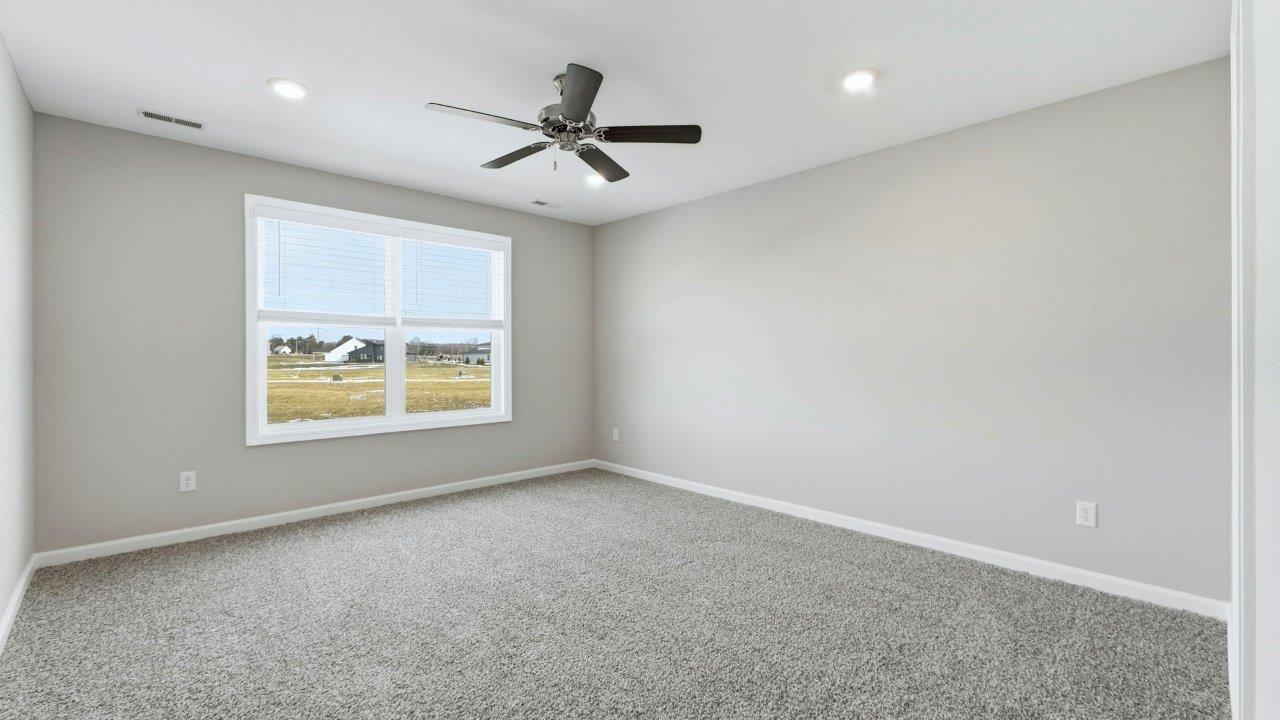 primary bedroom with carpet flooring, 2 windows, ceiling fan, and ensuite bath/closet