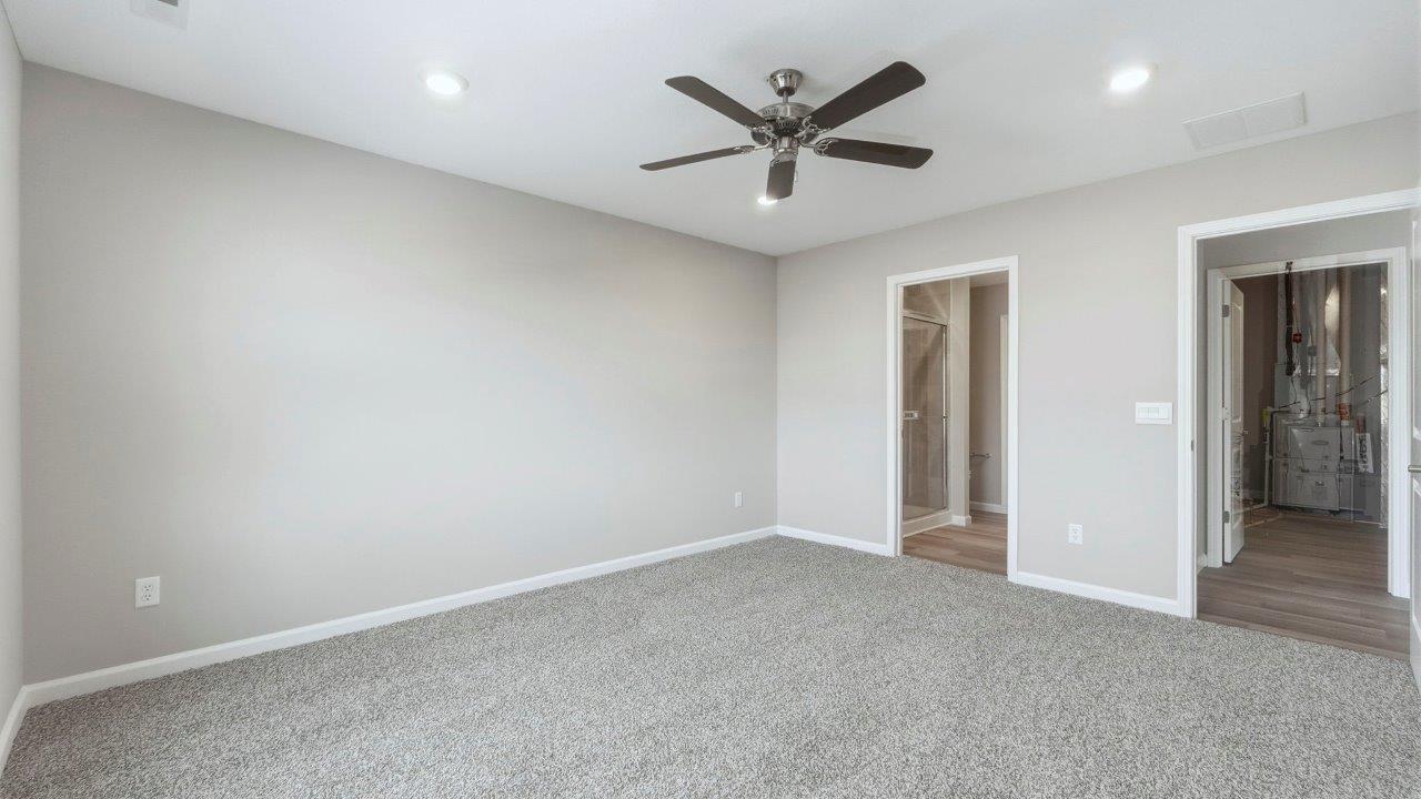 primary bedroom with carpet flooring, 2 windows, ceiling fan, and ensuite bath/closet
