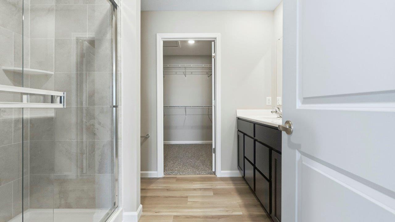 ensuite primary bath with dual sinks, sarsaparilla cabinets, and walk-in ceramic tile shower