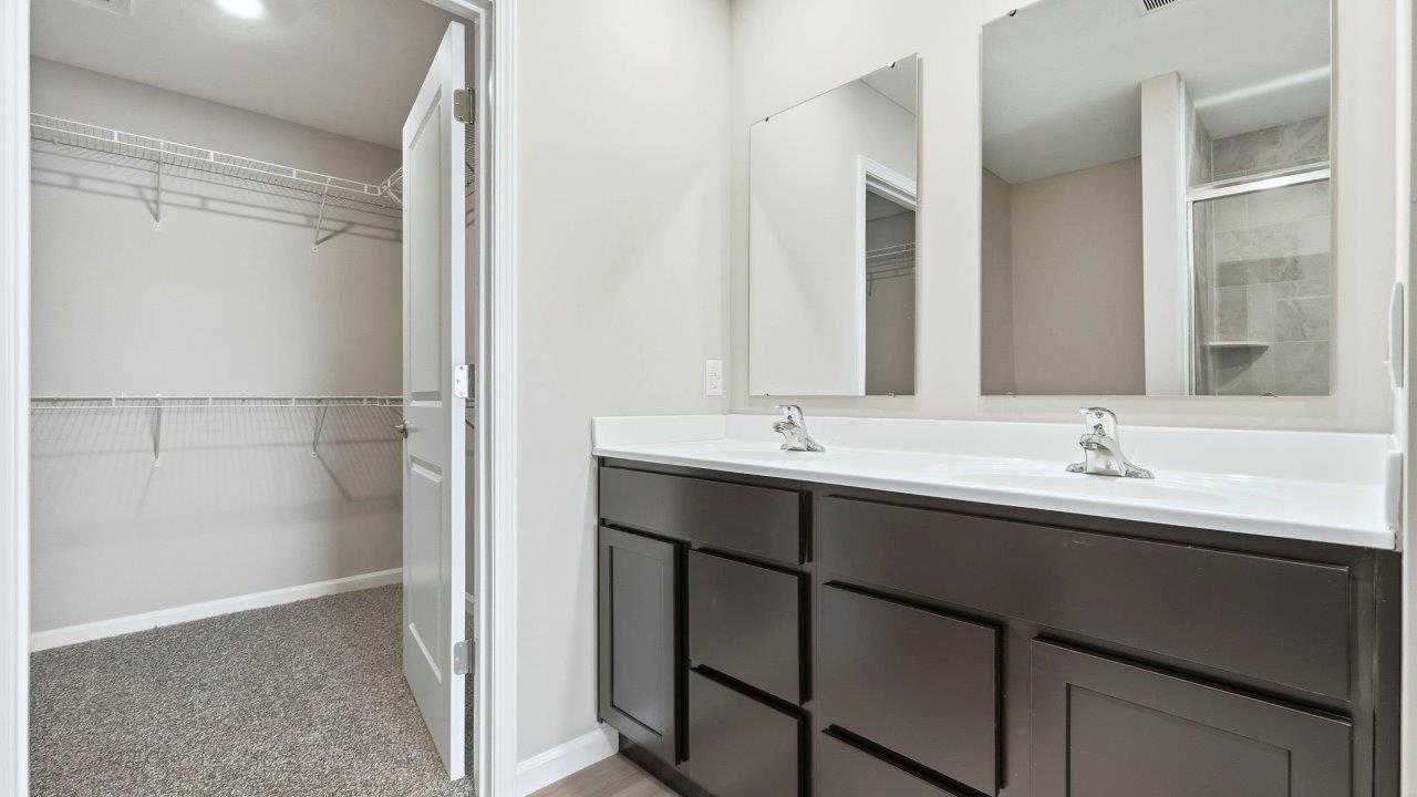ensuite primary bath with dual sinks, sarsaparilla cabinets, and walk-in ceramic tile shower