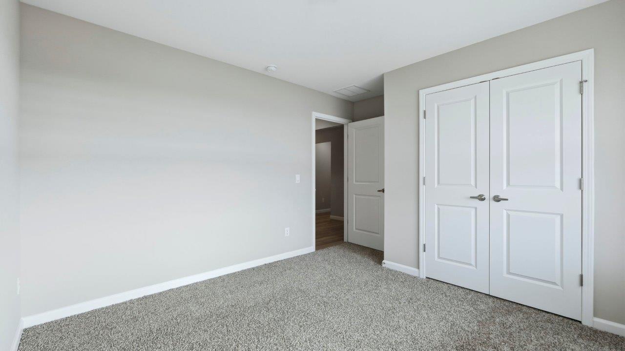 bedroom 2 front of home with carpet flooring, 2 windows, and closet