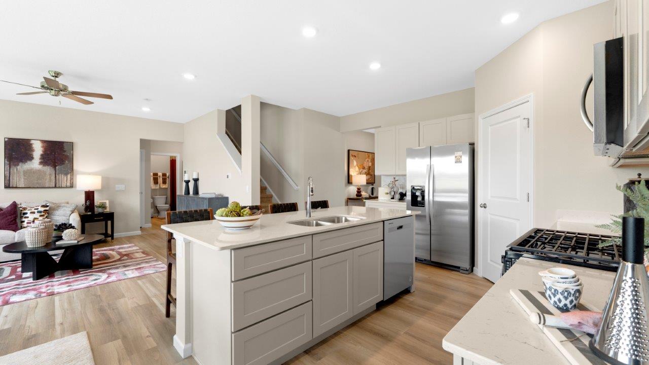 kitchen with white cabinets, quartz countertops, lvp flooring, corner pantry, large center island, and stainless steel appliances