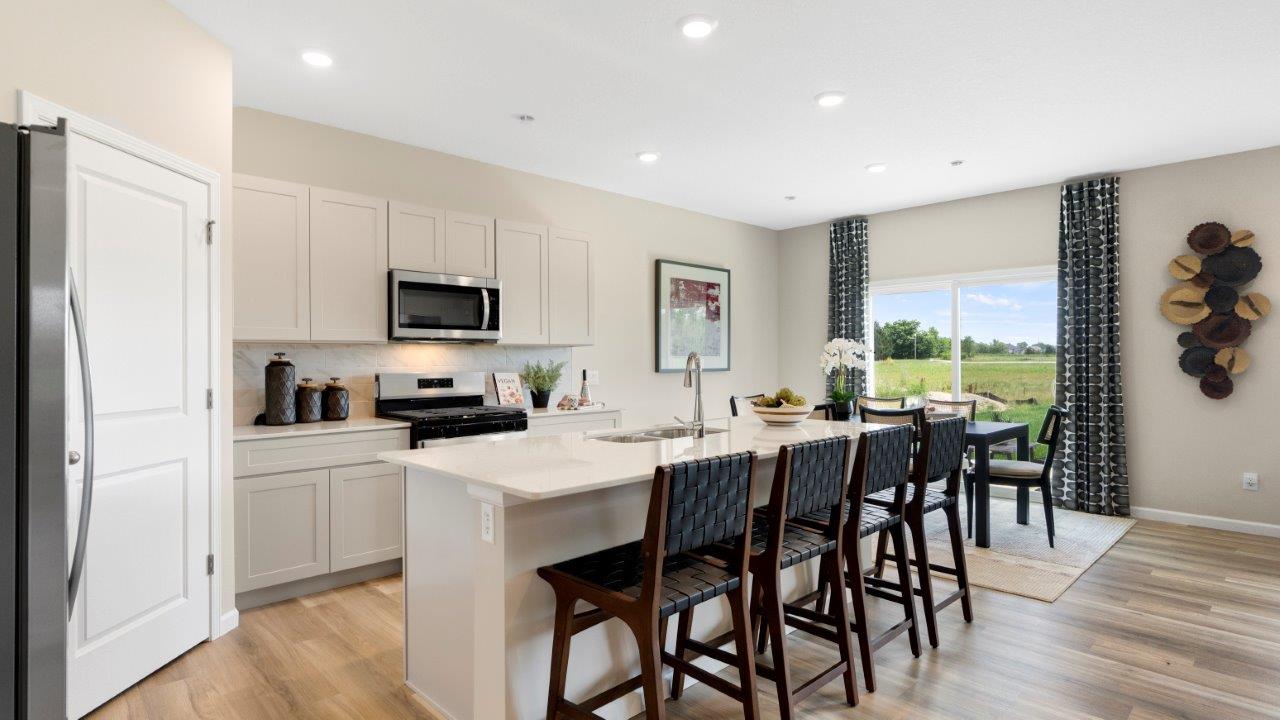 kitchen with white cabinets, quartz countertops, lvp flooring, corner pantry, large center island, and stainless steel appliances