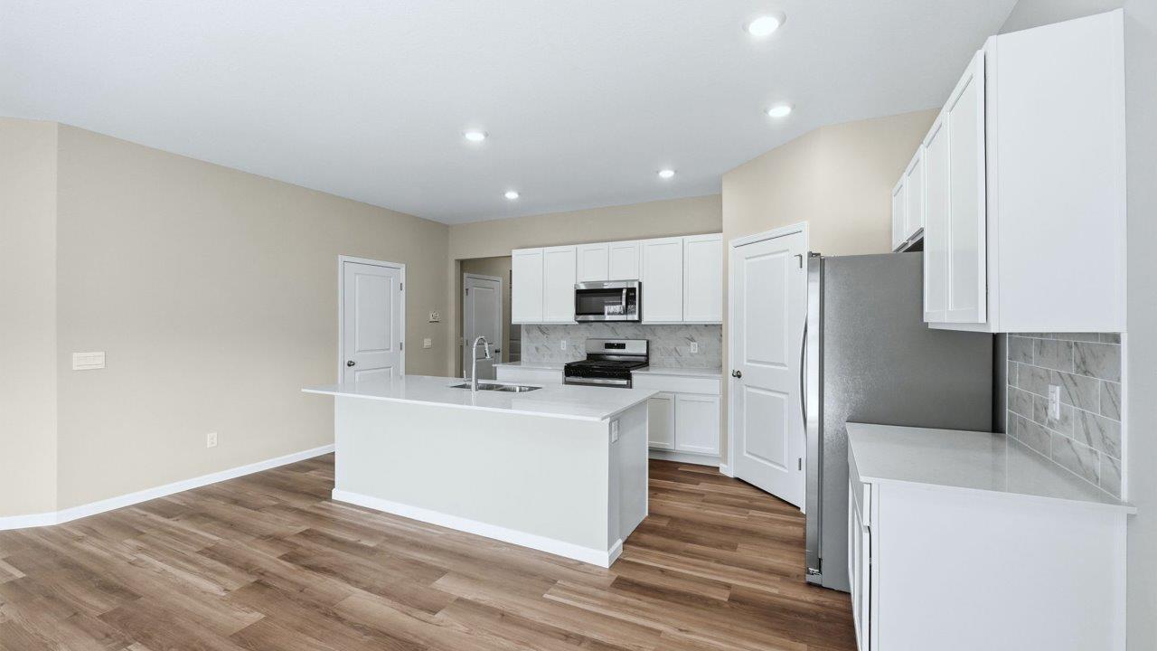 kitchen with white cabinets, quartz counters, corner pantry, stainless steel appliances, and center island with bar seating