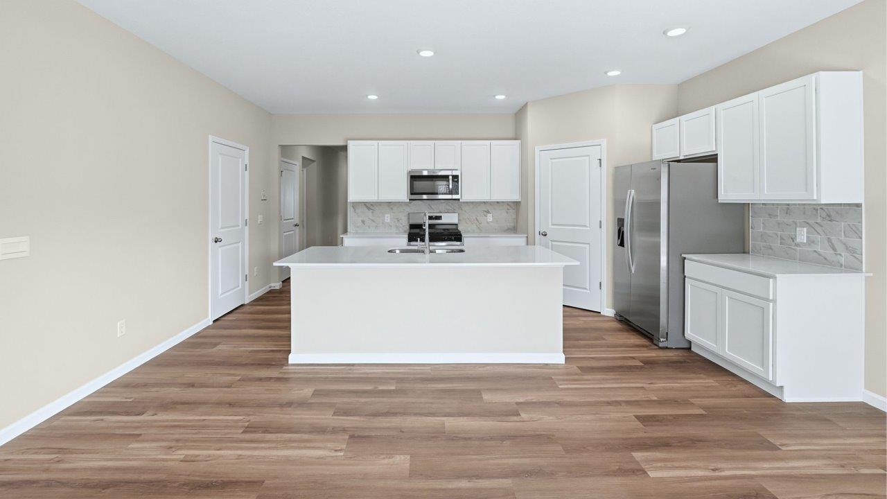 kitchen with white cabinets, quartz counters, corner pantry, stainless steel appliances, and center island with bar seating