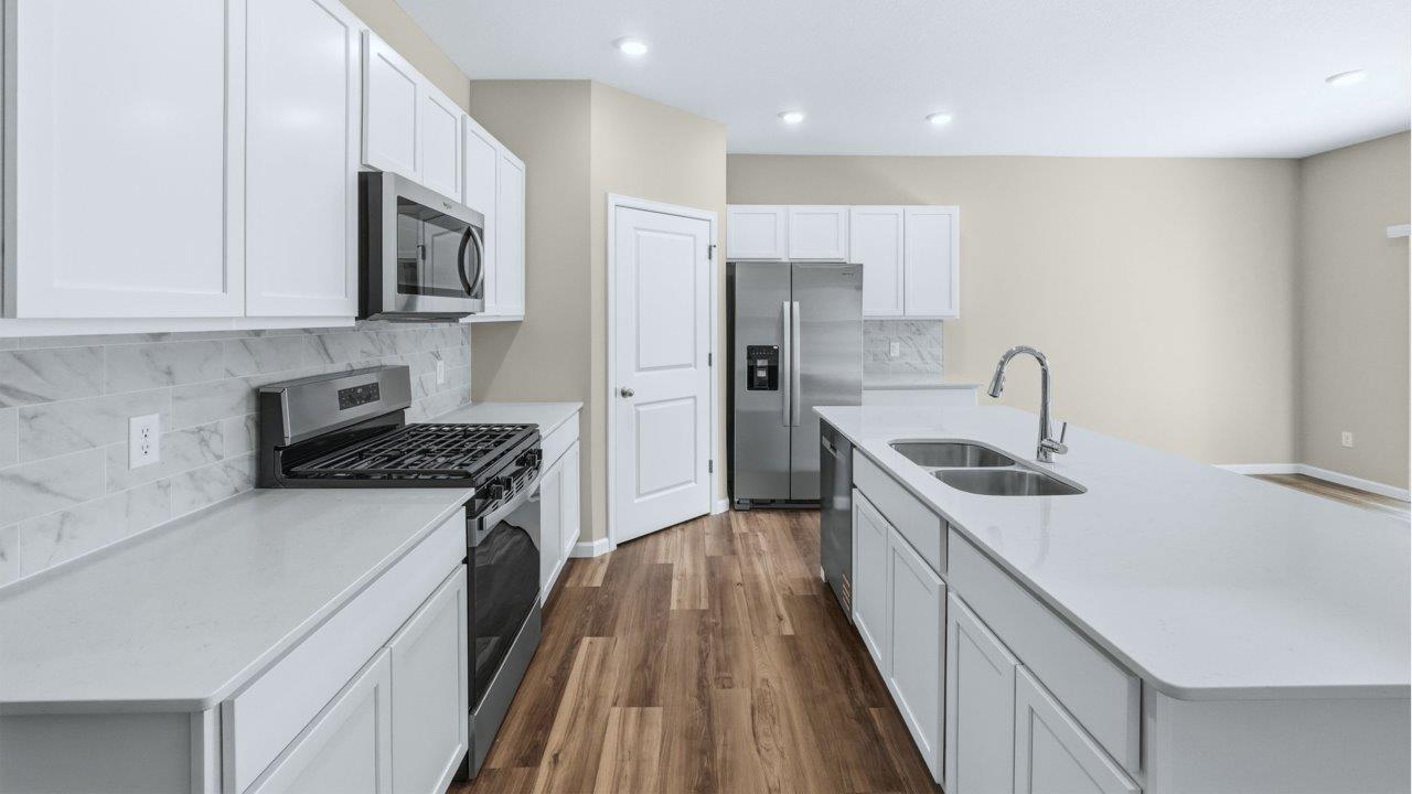 kitchen with white cabinets, quartz counters, corner pantry, stainless steel appliances, and center island with bar seating
