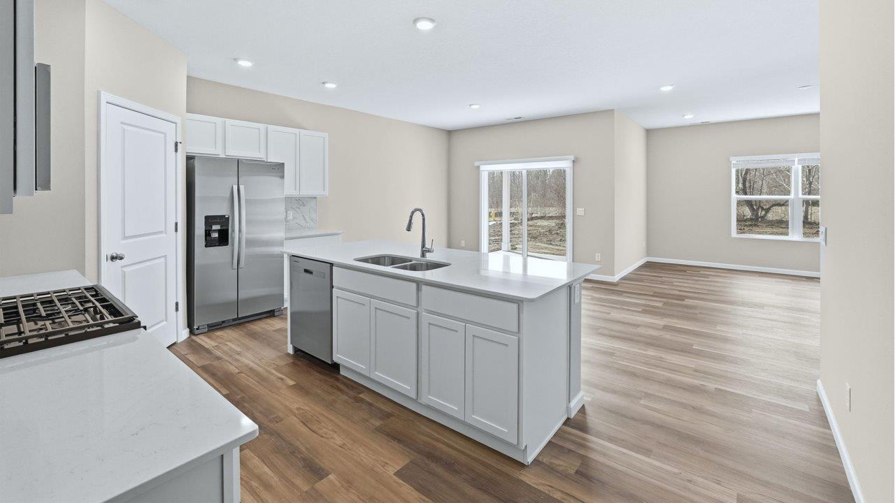 kitchen with white cabinets, quartz counters, corner pantry, stainless steel appliances, and center island with bar seating