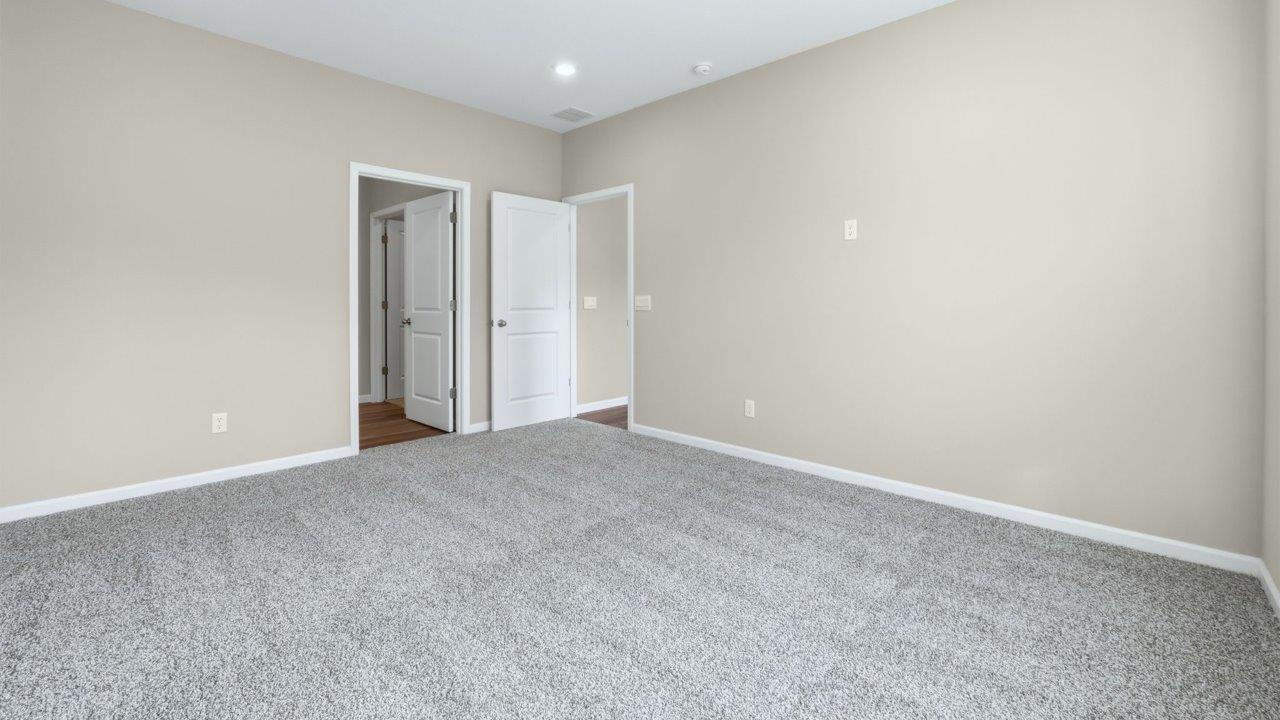 primary bedroom with 2 windows, carpet flooring, and ensuite bathroom and walk-in closet