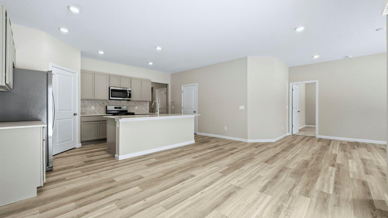 kitchen with grey shaker cabinets, center island, corner pantry, stainless steel appliances, and lyra quartz counters