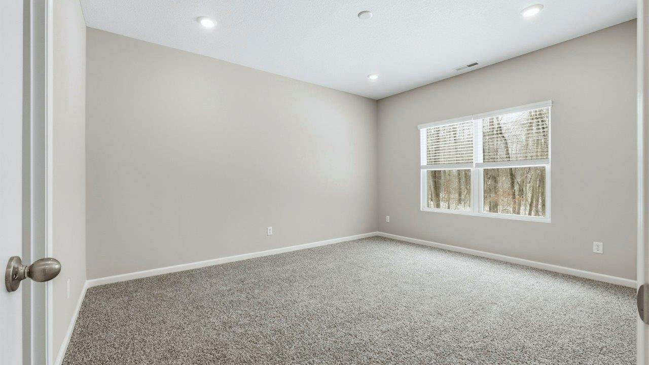 spacious primary bedroom with carpet, 2 windows, and ensuite bath and closet