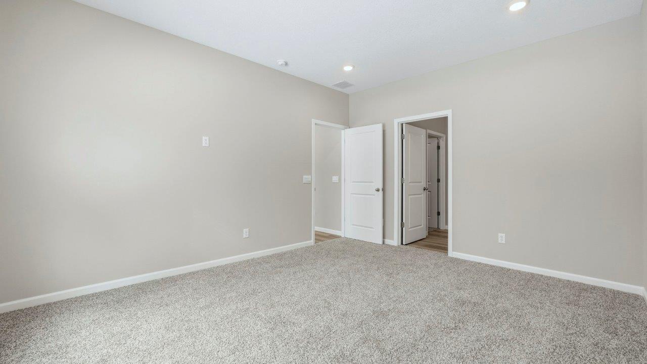 spacious primary bedroom with carpet, 2 windows, and ensuite bath and closet