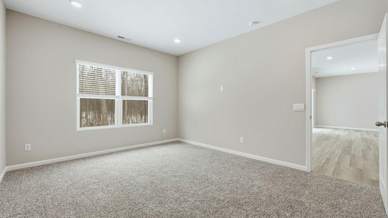 spacious primary bedroom with carpet, 2 windows, and ensuite bath and closet
