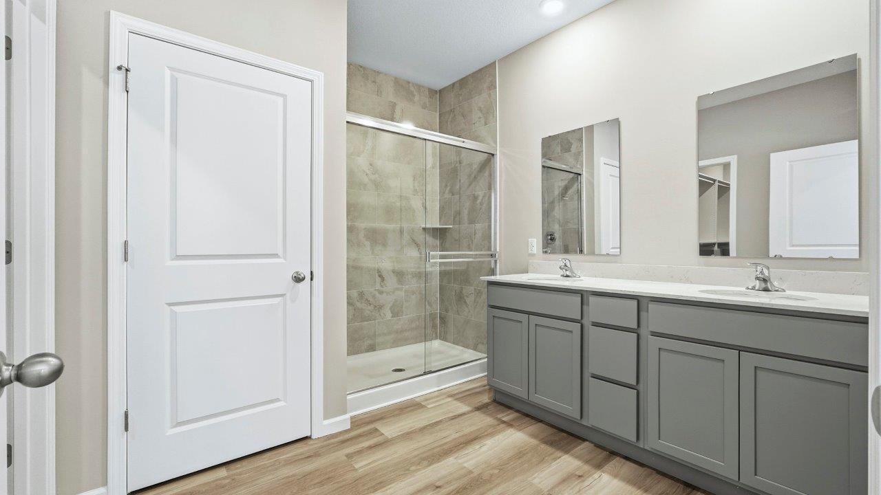 primary ensuite bathroom with dual sinks, lvp flooring, private water room, and ceramic tile shower