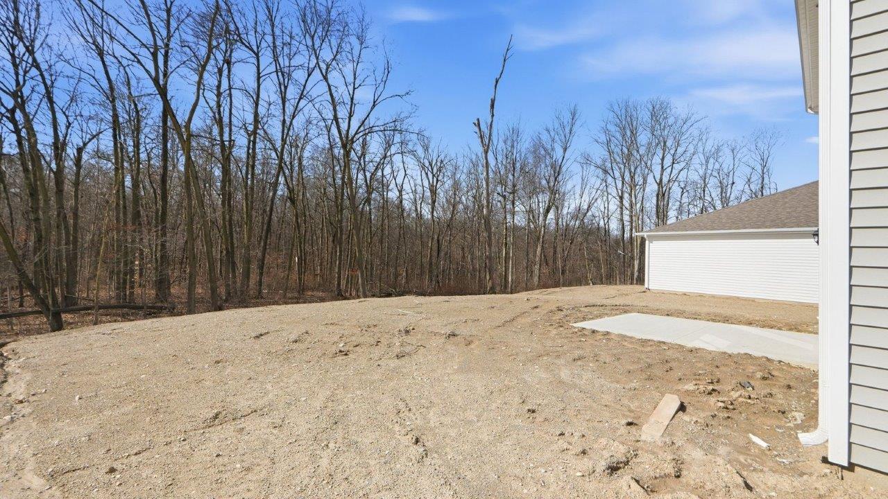 rear exterior with concrete patio and tree lined yard