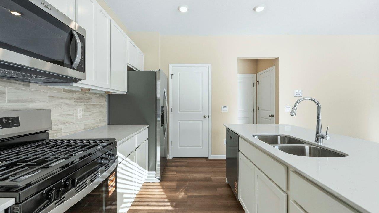 kitchen with white shaker cabinets, Whirlpool stainless steel appliances, quartz countertops, ceramic tile backsplash, and center island with built-in sink, dishwasher, and bar seating