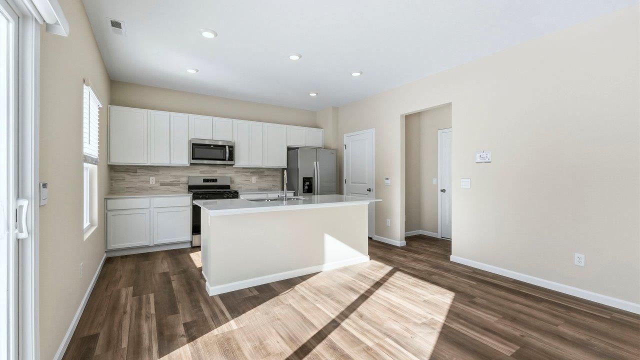 kitchen with white shaker cabinets, Whirlpool stainless steel appliances, quartz countertops, ceramic tile backsplash, and center island with built-in sink, dishwasher, and bar seating
