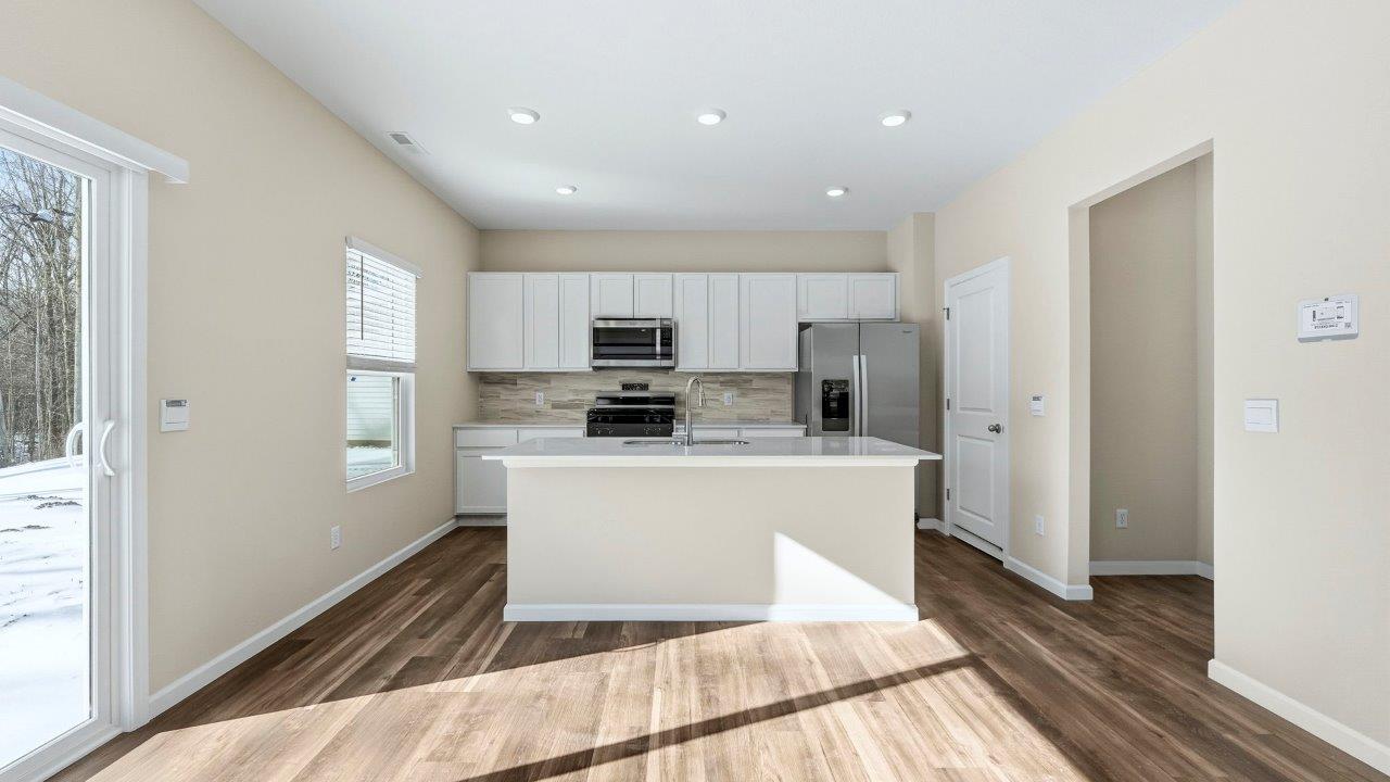 kitchen with white shaker cabinets, Whirlpool stainless steel appliances, quartz countertops, ceramic tile backsplash, and center island with built-in sink, dishwasher, and bar seating
