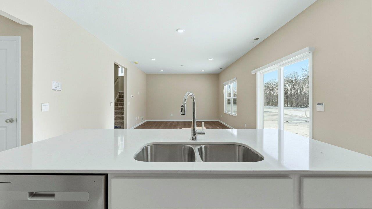 kitchen center island with white cabinets, quartz counters, and built-in sink and dishwasher
