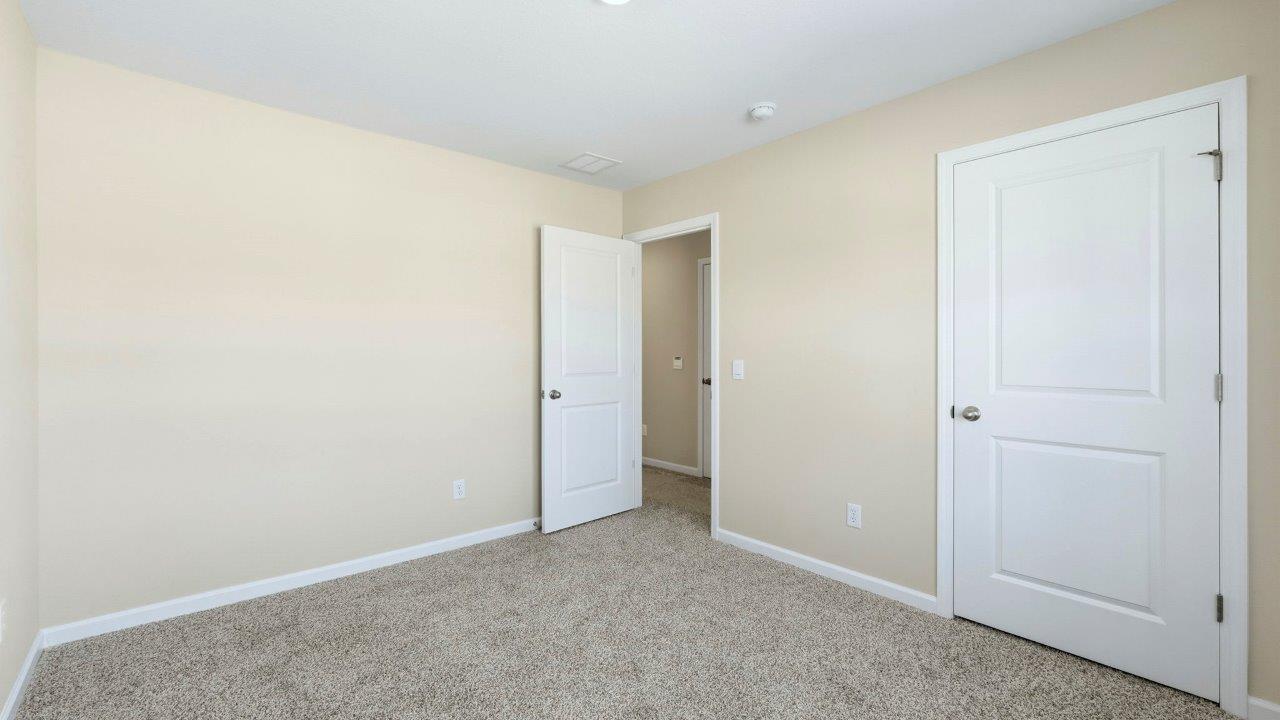 bedroom 4 with elk beige carpet, 2 windows, and a closet
