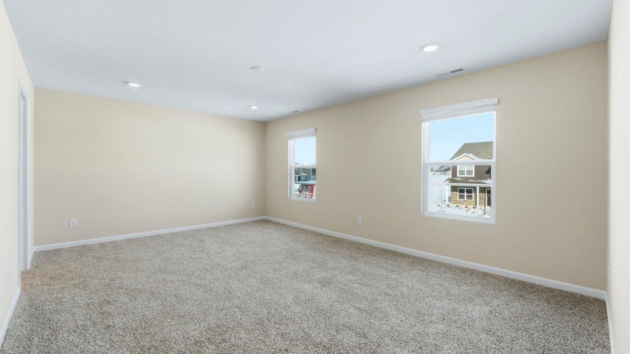 primary bedroom with elk beige carpet flooring, 2 windows, and ensuite bath and closet